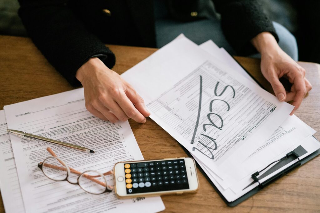 Publicidad engañosa de constructora: ¿Cómo actuar si te sientes estafado? Hands of a person examining tax forms labeled as scam with calculator and papers.